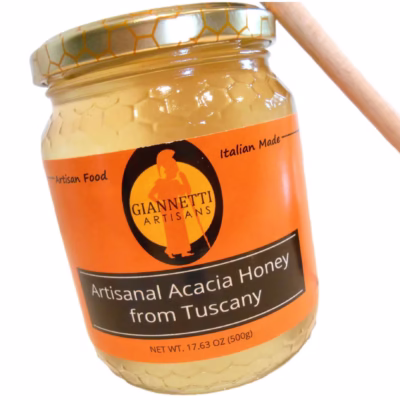 A 17.63 oz jar of Giannetti Artisans Italian Acacia Honey with honey dipper on side of the jar