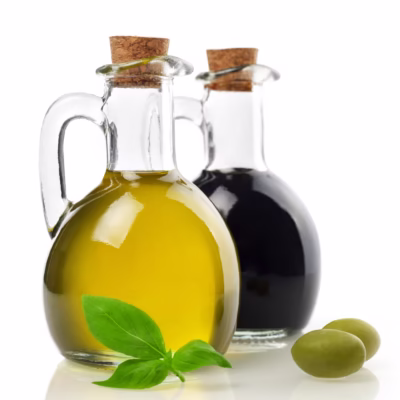 Round Olive Oil & Vinegar bottles with basil and olives on a white background for the Giannetti Artisans Artisan Olive Oil & Vinegar Collection