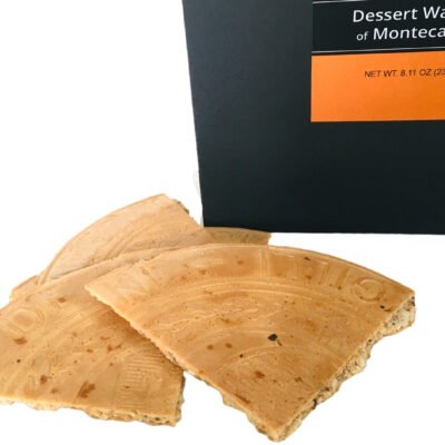 Close up of Giannetti Artisans montecatini wafer pieces with a partial view of the black packaging  on a white background